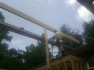 Carpenter setting a ridge beam over a new addition frame — Ice Dam Removal by Roofing Brothers in Annandale