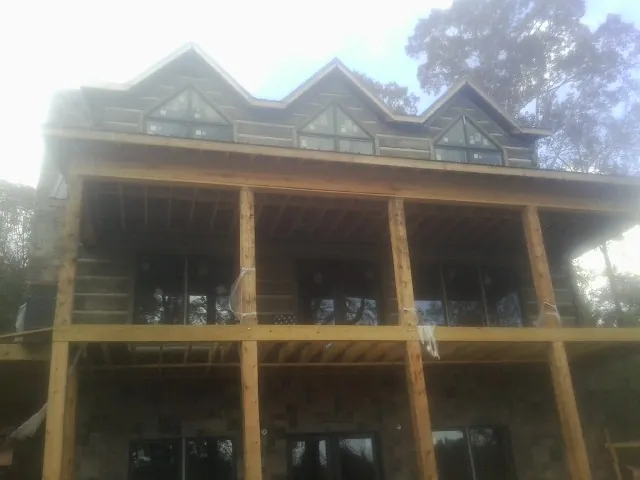 Dormers and porch framing on a large log home under construction — Roof Coating work by our crew in Annandale